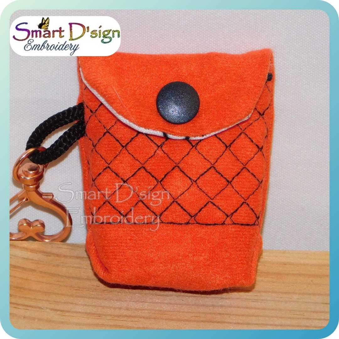 Orange fabric pouch with black button and keychain on a light gray background, branded 'Smart D'sign Embroidery'.