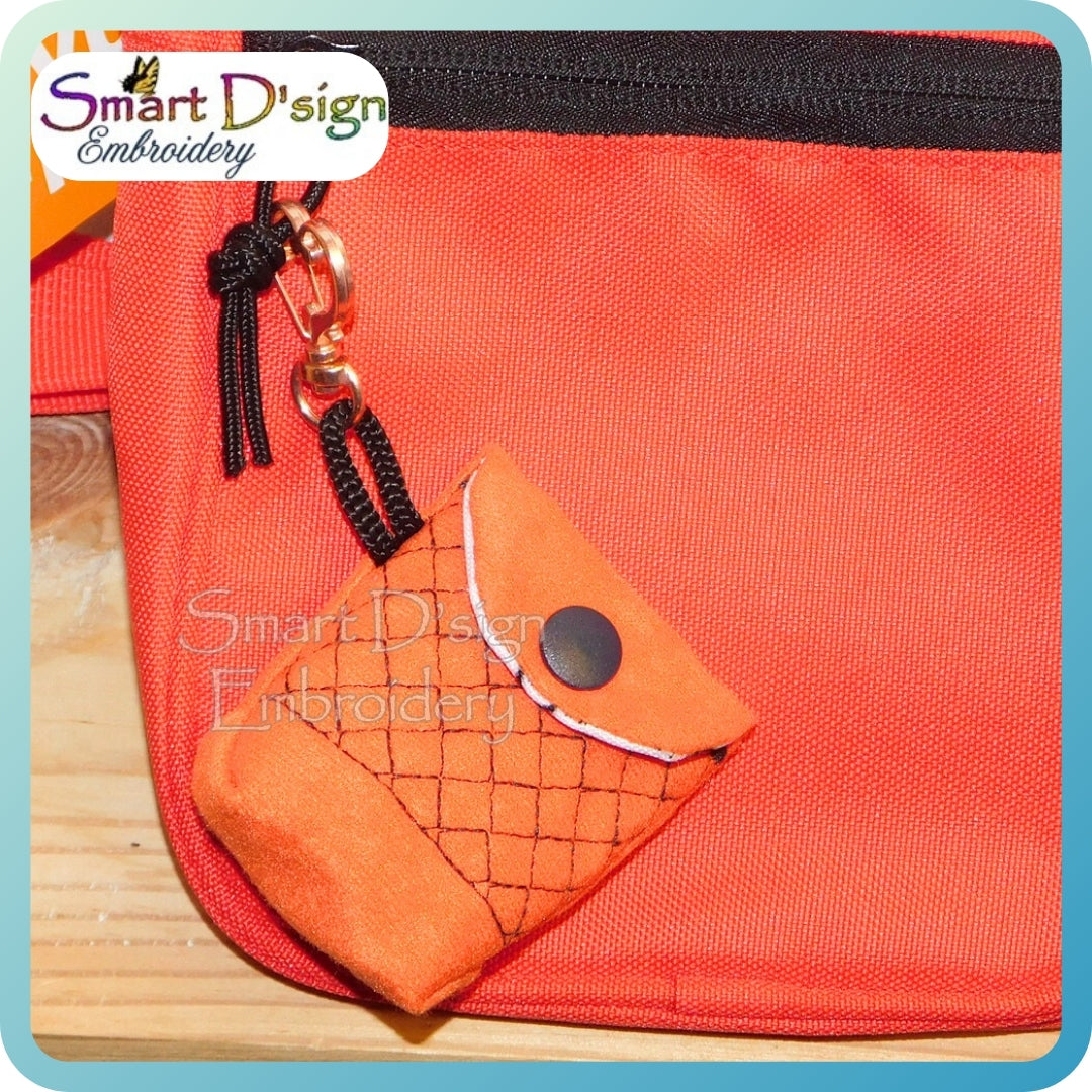 Red pouch with an orange fabric item and keychain on a wooden surface, branded 'Smart D'sign Embroidery'.