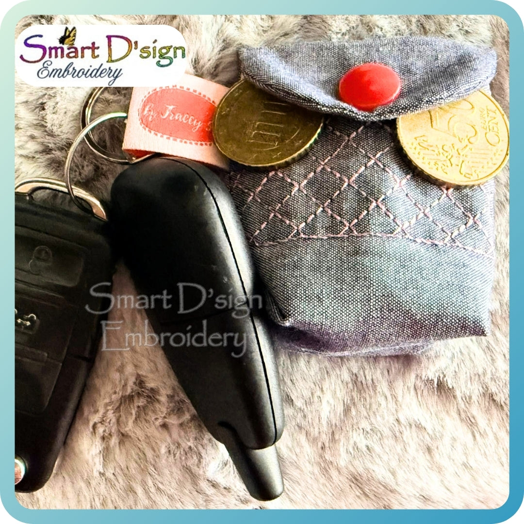Fabric pouch with coins and keychain on a textured surface, branded 'Smart D'sign Embroidery'.